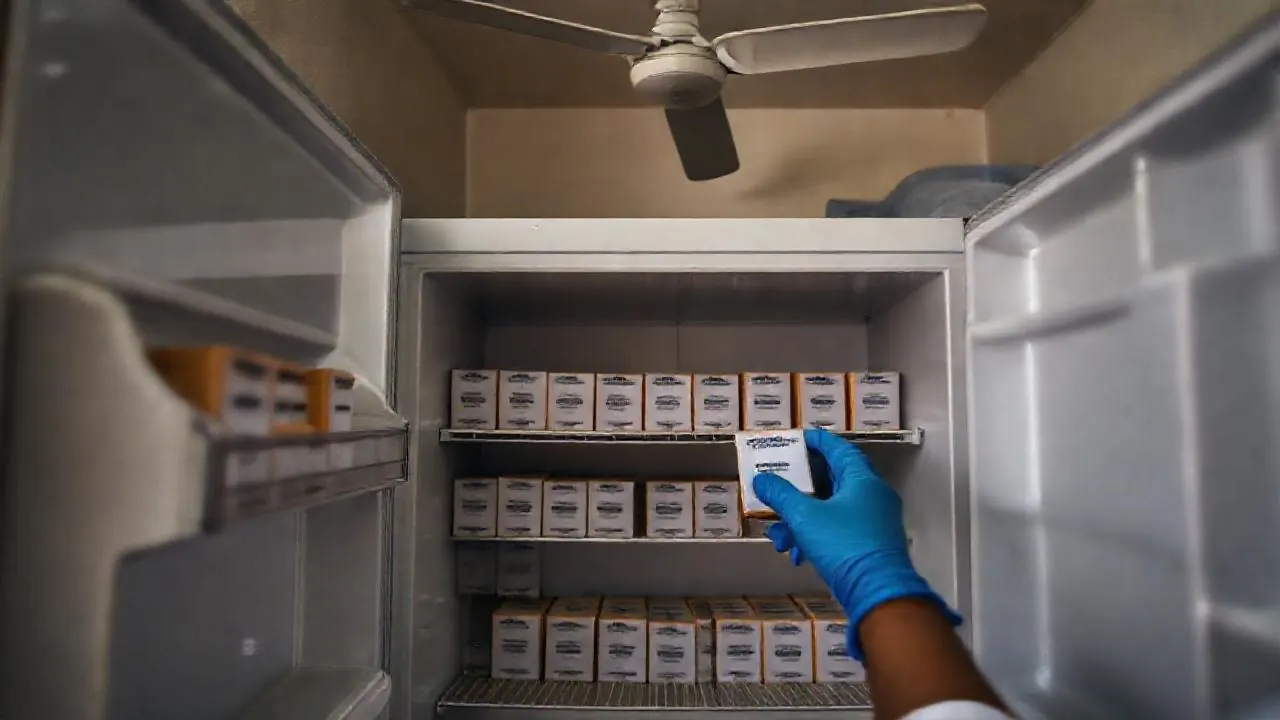 Pharmacist's gloved hands take a vaccine box from a clinic fridge, where the anti-rabies injection is free in India
